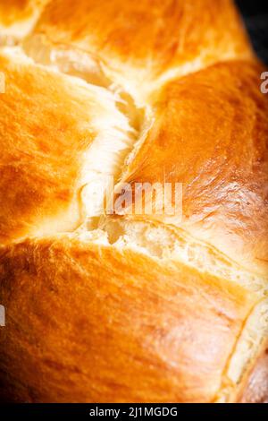 Bel pane dorato cotto a tre treccia con lavaggio delle uova. Challah è un pane speciale di origine ebraica Ashkenazi, solitamente intrecciato e consumato tipicamente Foto Stock