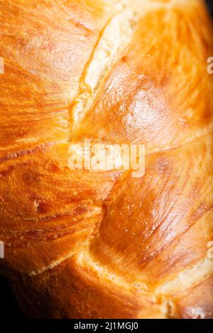 Bel pane dorato cotto a tre treccia con lavaggio delle uova. Challah è un pane speciale di origine ebraica Ashkenazi, solitamente intrecciato e consumato tipicamente Foto Stock