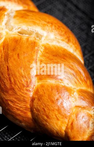 Bel pane dorato cotto a tre treccia con lavaggio delle uova. Challah è un pane speciale di origine ebraica Ashkenazi, solitamente intrecciato e consumato tipicamente Foto Stock