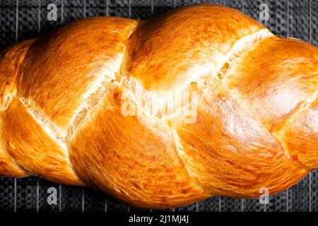 Bel pane dorato cotto a tre treccia con lavaggio delle uova. Challah è un pane speciale di origine ebraica Ashkenazi, solitamente intrecciato e consumato tipicamente Foto Stock