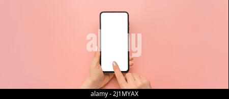 Tenere il dispositivo cellulare e toccare lo schermo su sfondo rosa. Cellulare mockup. Cellulare femmina con tenuta di mano. Smartphone con schermo vuoto Foto Stock