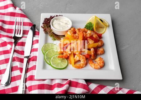 Gamberetti piccanti all'aglio in piatto bianco su sfondo grigio Foto Stock