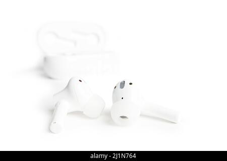 Primo piano: Auricolari TWS (True Wireless stereo) bianchi isolati su sfondo bianco. Messa a fuoco superficiale. Foto Stock