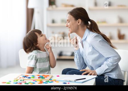 Formazione vocale per bambini. Formazione professionale della donna con il ragazzino al gabinetto, insegnamento delle esercitazioni di articolazione destra Foto Stock