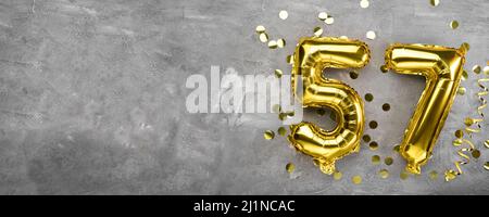 Numero palloncino di foglio giallo, numero cinquantasette sfondo concreto. Biglietto d'auguri con l'iscrizione 57. Concetto di anniversario. Per anniversario Foto Stock