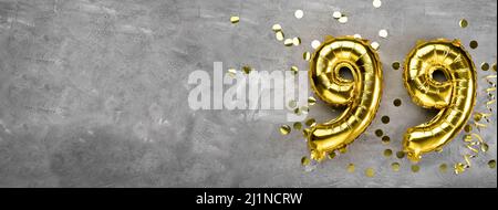 Palloncino di alluminio giallo numero novantanove su sfondo concreto. Biglietto d'auguri con l'iscrizione 99. Concetto di anniversario. Per anniversario, compleanno Foto Stock