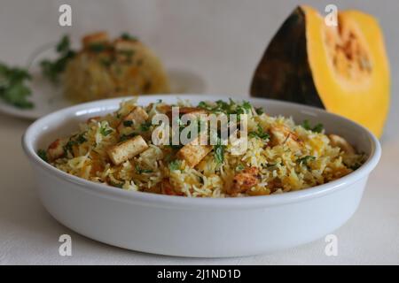 Formaggio di zucca riso cottage. Una pentola per la preparazione del riso con riso basmati, zucca grattugiata e spezie, con cubetti di formaggio caserario fritto in padella. Comune Foto Stock