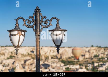 Vista ad angolo basso di una lampada stradale contro un pallone ad aria calda nel cielo blu della cappadocia. Foto Stock