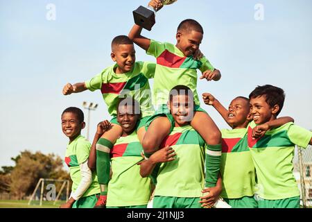 Gioca con passione e vincerai. Scatto di una squadra di calcio ragazzi che celebra la loro vittoria su un campo sportivo. Foto Stock