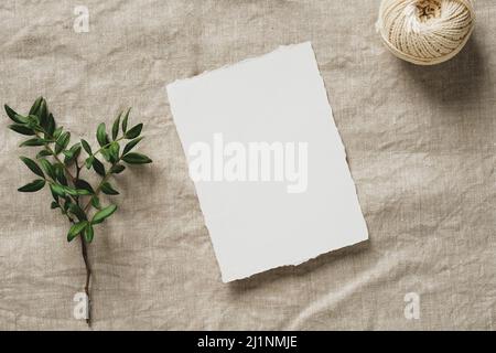 Carta d'invito per matrimoni, ramo verde, corda su tela di lino. Disposizione piatta, vista dall'alto, spazio di copia. Foto Stock