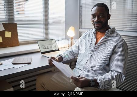 Ritratto di un imprenditore nero sorridente che guarda la fotocamera mentre si siede in ufficio a casa, spazio copia Foto Stock