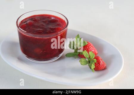 Salsa di fragole. Preparato a partire da fragole fresche bollite e ridotte a una consistenza di salsa addizionata di zucchero. Scatto su sfondo bianco Foto Stock