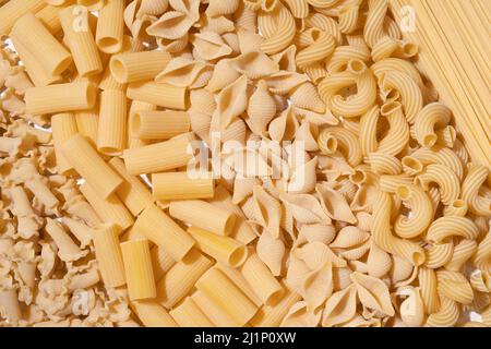Diversi tipi di pasta cruda su sfondo tessile Foto Stock