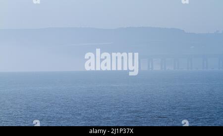 Dundee, Tayside, Scozia, Regno Unito. 27th marzo 2022. Tempo britannico: A causa dell'aria fredda proveniente dall'ovest, si forma una bassa nebbia densa attraverso il fiume Tay, creando viste mozzafiato su Dundee. Le temperature scesero a 14°C. Più tardi nel giorno, il sole disperde la nebbia, permettendo al sole caldo di brillare e le temperature nella Scozia nord-orientale per raggiungere i 18°C. Viste spettacolari dal lungofiume di Dundee del Ponte di Tay Road, il Fiume Tay, il Ponte della Ferrovia di Tay e il Museo del Design V&A in primavera. Credit: Dundee Photographics/Alamy Live News Foto Stock