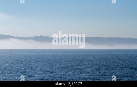 Dundee, Tayside, Scozia, Regno Unito. 27th marzo 2022. Tempo britannico: A causa dell'aria fredda proveniente dall'ovest, si forma una bassa nebbia densa attraverso il fiume Tay, creando viste mozzafiato su Dundee. Le temperature scesero a 14°C. Più tardi nel giorno, il sole disperde la nebbia, permettendo al sole caldo di brillare e le temperature nella Scozia nord-orientale per raggiungere i 18°C. Viste spettacolari dal lungofiume di Dundee del Ponte di Tay Road, il Fiume Tay, il Ponte della Ferrovia di Tay e il Museo del Design V&A in primavera. Credit: Dundee Photographics/Alamy Live News Foto Stock