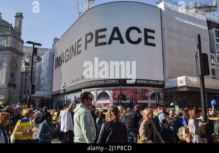 Il messaggio 'Imagine Peace' dell'artista e cantante Yoko Ono è esposto su Piccadilly Lights a Piccadilly Circus durante la marcia 'London Stands with Ukraine'. Migliaia di persone hanno marciato da Park Lane a Trafalgar Square in solidarietà con l'Ucraina mentre la Russia continua il suo attacco. Foto Stock