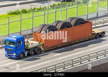 Trasporto di enormi ruote di autocarro di scarico in un container su un rimorchio. Foto Stock