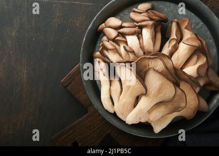 Funghi di ostrica freschi. Stira una vecchia ciotola di deliziosi funghi ostrica biologici su un vecchio sfondo di legno, vista dall'alto con spazio per il testo. Foto Stock