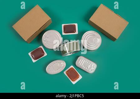 Set di alimenti in scatola, terrine scatole di cartone su sfondo verde. Foto Stock