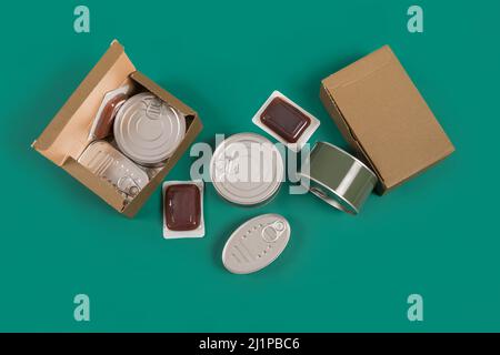 Set di alimenti in scatola, terrine scatole di cartone su sfondo verde. Foto Stock