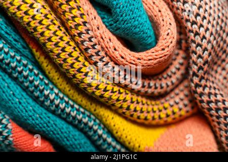 Pieghe ritorte di tessuti colorati a maglia di abiti invernali con strutture e tessuti diversi. Sfondo con forme uniformi. Multi colo piegato liscio Foto Stock