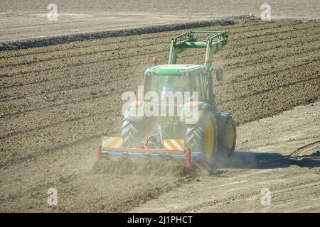 Agricoltore in trattore che prepara la terra con coltivatore a basamento come parte delle attività di pre-semina all'inizio della stagione primaverile. Cuneo, Italia - Marzo 2022 Foto Stock