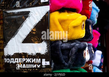 Mosca, Russia. 27th marzo 2022 T-shirt con segno Z e cappelli dell'esercito sovietico al banco di un negozio di souvenir in via Arbat nel centro di Mosca, Russia. L'iscrizione sulla t-shirt recita 'sosterrò il nostro' Foto Stock