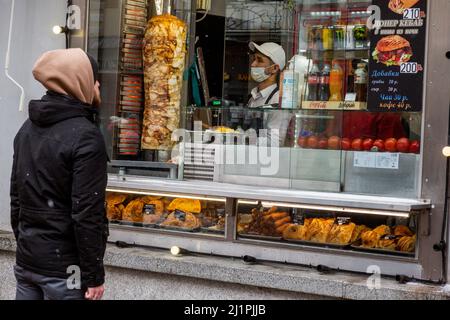 Mosca, Russia. 27th marzo 2022 Un uomo in una bancarella di Street food che vende shawarma per un cliente in via Arbat a Mosca, Russia Foto Stock