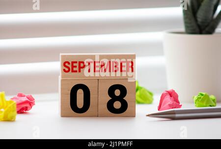 Settembre 8. Data del mese di settembre. Cubo di numeri con un fiore e un quaderno su tavolo in legno Diamond per lo sfondo. Foto Stock