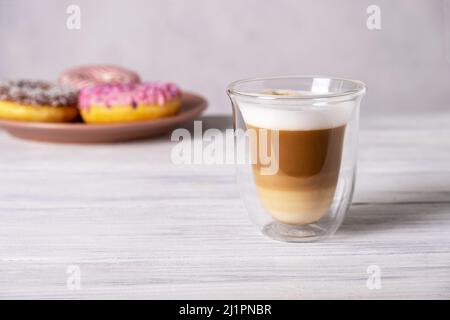 Ciambelle decorate con vetri su piatti e latte di caffè o cappuccino Foto Stock