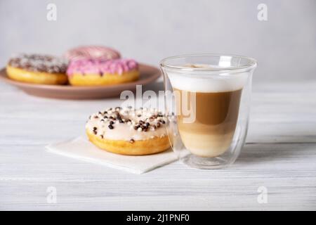 Ciambelle decorate con vetri su piatti e latte di caffè o cappuccino Foto Stock