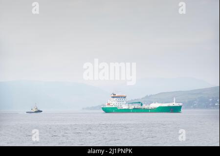 Nave che trasporta container galleggiante in mare seguito da rimorchiatore Foto Stock