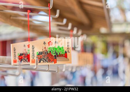 kyushu, giappone - marzo 13 2022: Placche di Ema in legno Giapponese decorate con un disegno del ponte rosso Taiko Bashi del Santuario shinto di Dazaifu e adornate Foto Stock