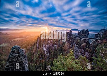 Paesaggio con le formazioni rocciose Felsenburg Neurathen e Bastei nella zona di Rathen del Parco Nazionale della Svizzera Sassonia all'alba in autunno. Foto Stock
