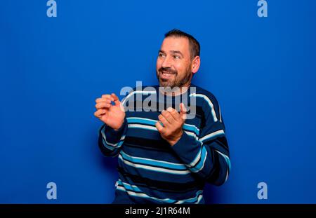 Giovane bell'uomo a righe su fondo blu isolato, stressato e imbarazzato. Ansia problema. Foto Stock