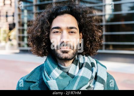 Ritratto urbano del giovane curly con barba in posa sulla strada Foto Stock