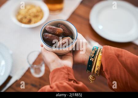 Rompendo il mio veloce il senso tradizionale. Shot di una donna musulmana che tiene una ciotola di date per rompere il suo digiuno. Foto Stock