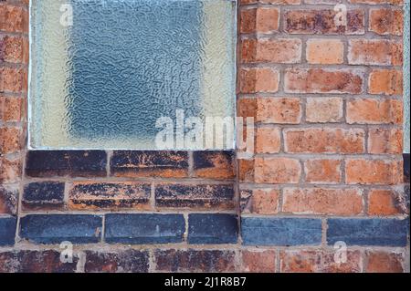 immagine di sfondo del modello della finestra smerigliata sul vecchio muro di mattoni rossi con linea di mattoni neri Foto Stock