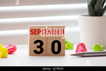 Settembre 30. Data del mese di settembre. Cubo di numero con un fiore e legno segno su tavolo di legno Diamante per lo sfondo. Foto Stock