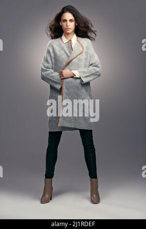Incredibile in inverno couture. Studio girato di una giovane donna vestita elegantemente su sfondo grigio. Foto Stock
