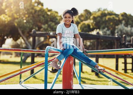 Vorrei poter giocare al parco tutto il giorno. Ritratto a tutta lunghezza di una bambina adorabile che gioca su un merry-go-round al parco. Foto Stock