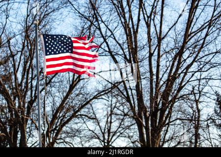 Bandiera americana gravemente lacerata che vola da flagpole all'esterno Foto Stock