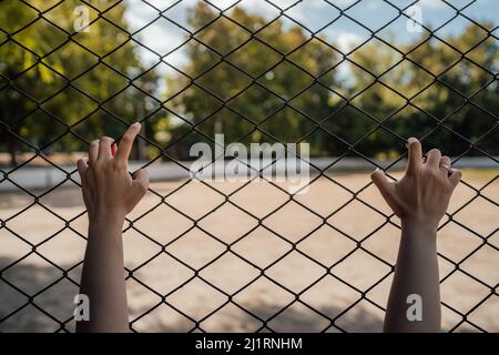 Le mani sul reticolo simboleggiano la limitazione in qualcosa. Foto Stock