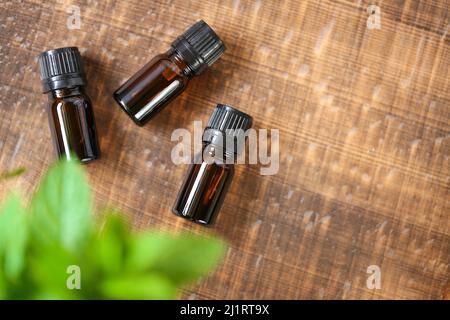 Olio essenziale di menta piperita.bottiglia di vetro e menta piperita fresca su sfondo di legno.Aromatherapy e cosmetici naturali biologici. Foto Stock