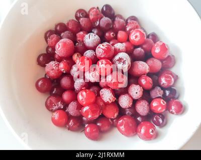 Primo piano di mirtilli rossi congelati e mirtilli rossi in un piatto, sfondo di frutti di bosco ricoperto di ghiaccio. Una bacca luminosa e succosa è molto utile per Foto Stock