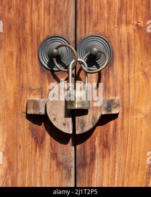 Primo piano di maniglie delle porte in ottone e serratura appesa su sfondo di legno di pino tonalità oro Foto Stock