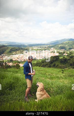 Non è richiesto alcun guinzaglio. Scatto a tutta lunghezza di un bel giovane uomo che prende il suo cane per una passeggiata in montagna. Foto Stock