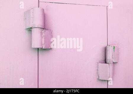 Primo piano delle cerniere metalliche sui cancelli di un garage in metallo, verniciato di rosa, all'aperto Foto Stock