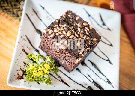 Deliziosa torta brownie su un piatto bianco con salsa al cioccolato. Dolce dessert con semi di girasole. Primo piano Foto Stock