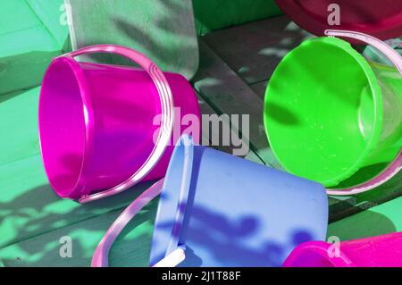 Stoviglie in plastica pulita e multicolore, vuote, su sfondo di legno, all'aperto, in una giornata di sole Foto Stock